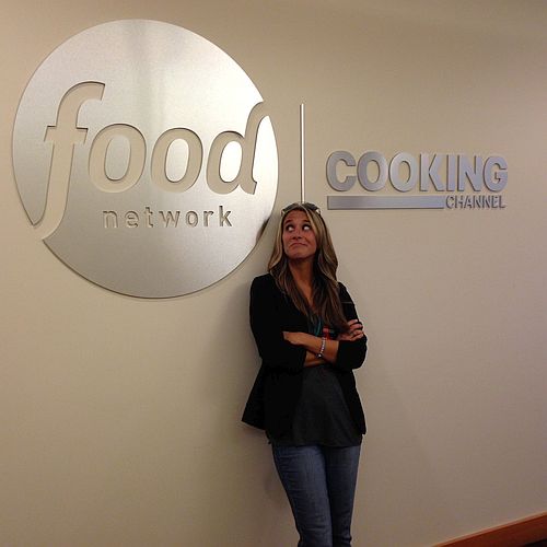 Fanny Slater posing in front of the Food Network wall logo and sign